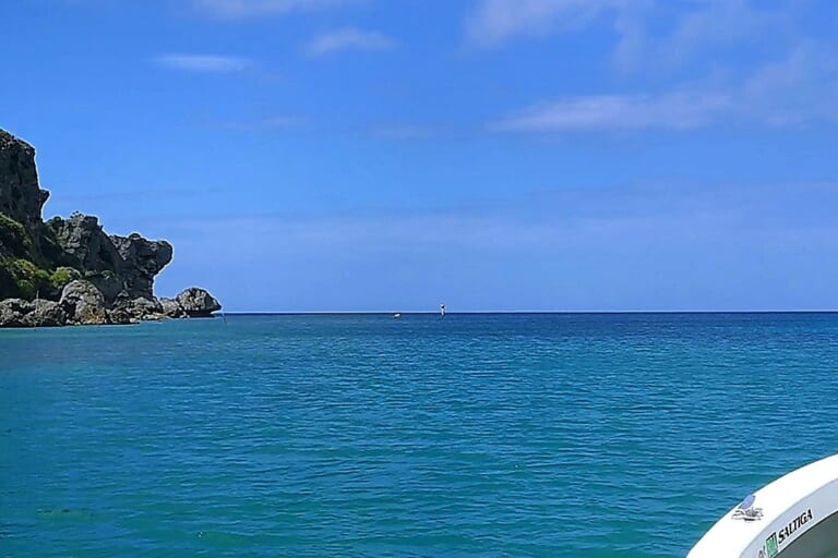 真っ青な沖縄の海と空。水平線とそこに浮かぶ岩礁帯。