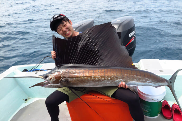 釣り上げたセイルフィッシュを持つ釣り人